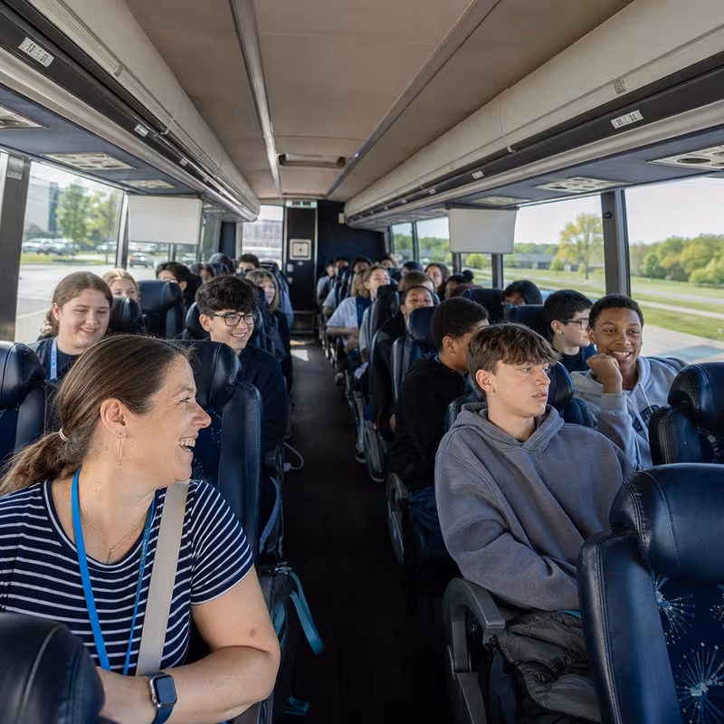 Group boarding a white charter bus for School Transportation transportation in Lakewood